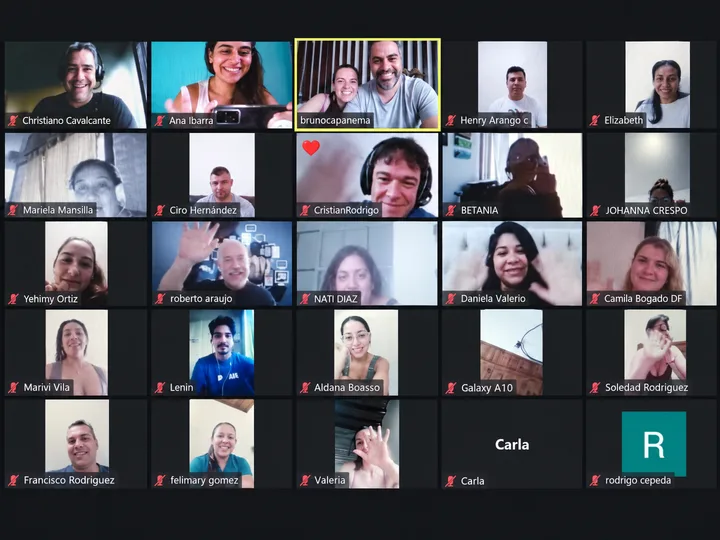 Participantes de una reunión grupal saludando a cámara.